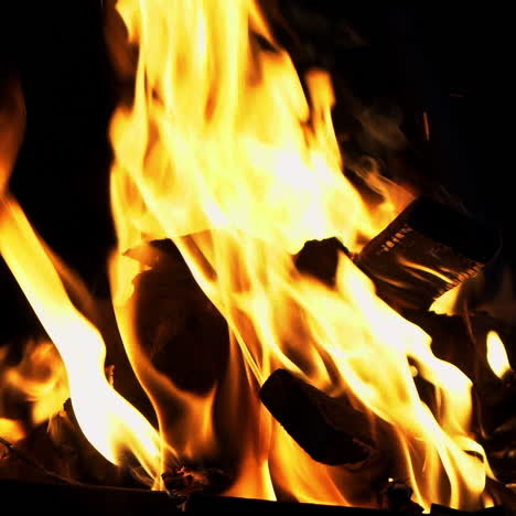 smoldered logs burned in vivid fire at night. atmospheric background with orange flame of campfire. unimaginable detailed image of bonfire from inside.