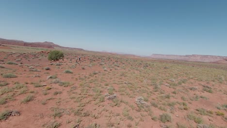 Two-people-walking-through-the-stunning-desert-landscape-of-Indian-Creek,-surrounded-by-towering-sandstone-formations-and-ancient-cultural-history