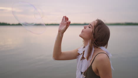 a young female artist shows a soap bubble show by blowing up large soap bubbles with her hands in slow motion