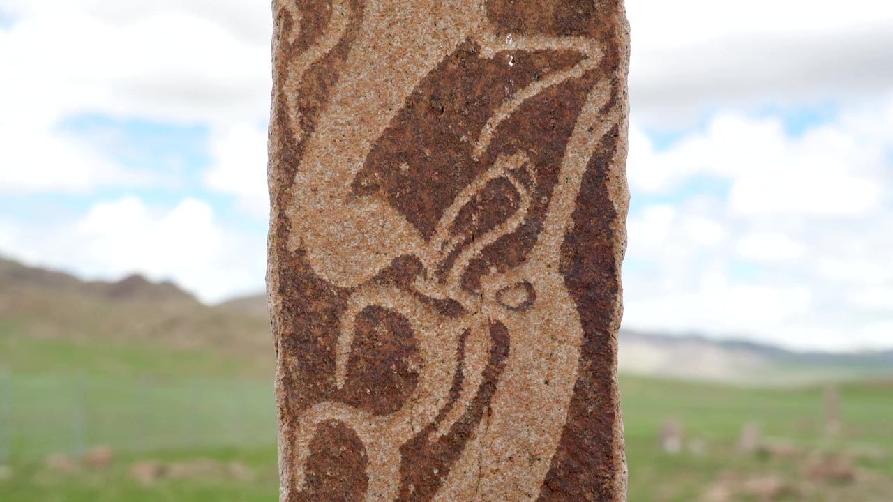 Antica stele di pietra con intagli intricati nella steppa mongola.