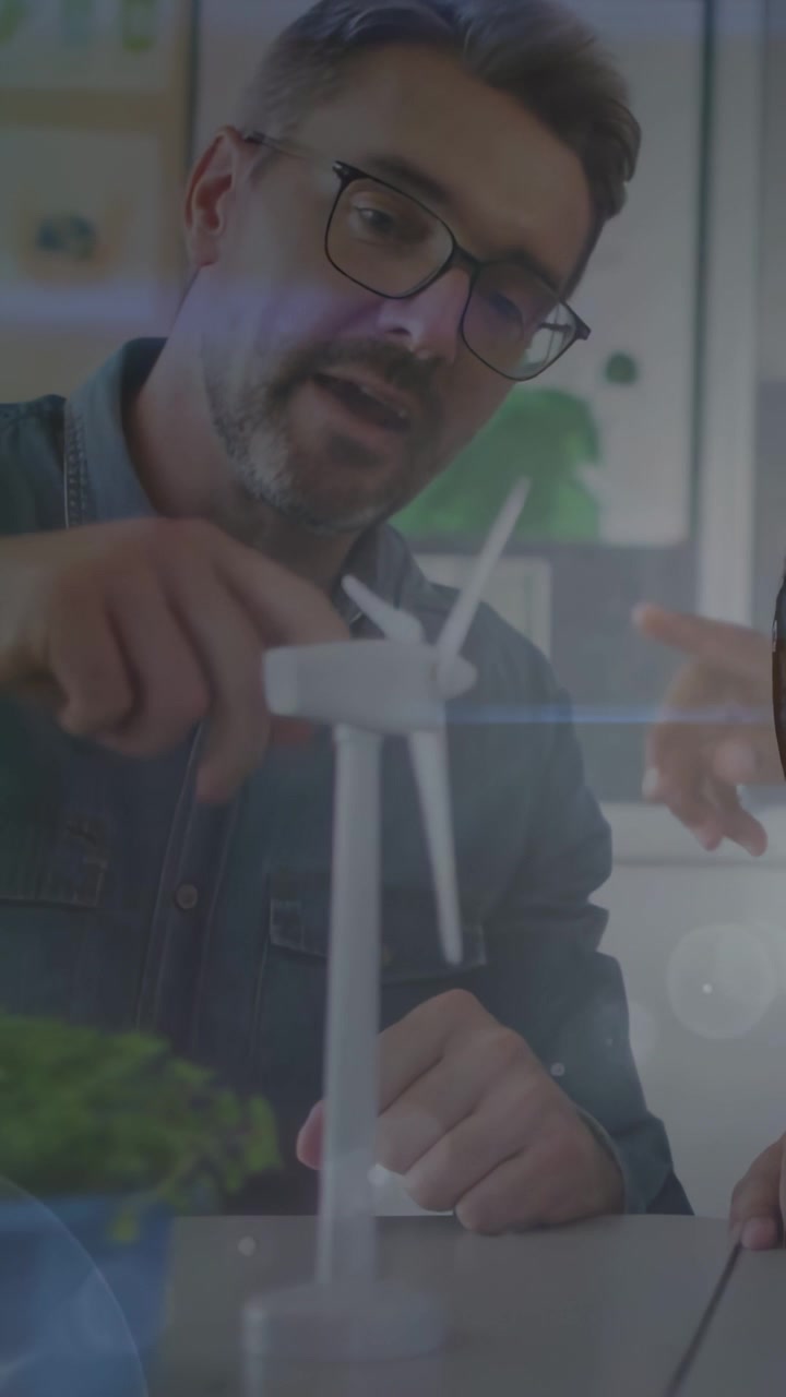 Vertical video: Man nudging tabletop wind turbine blades after child pointing teaching environment