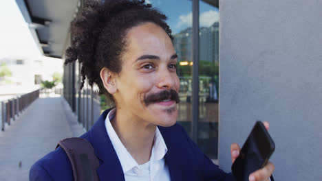 mixed race man with moustache walking on the street and talking on smartphone