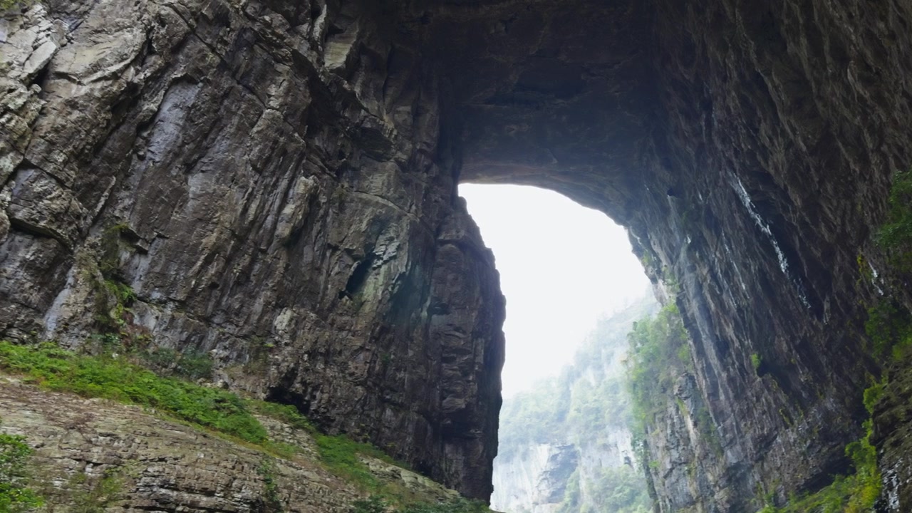 Massive Naturstein-Bogenbrücken überspannen eine tiefe Schlucht im Landschaftsgebiet der Drei Naturbrücken in Chongqing, China. Schwenkaufnahme