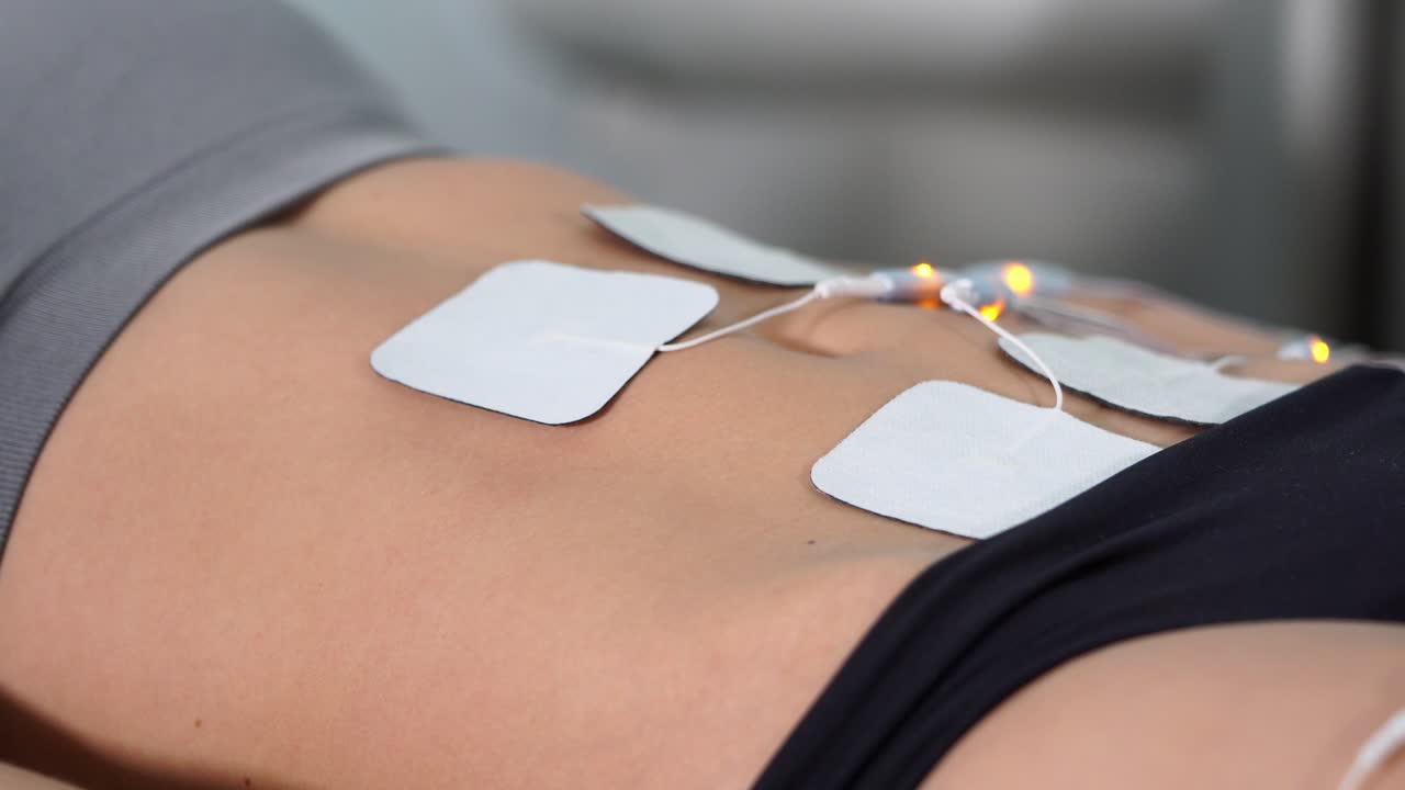 Woman receiving TENS unit treatment on abdomen