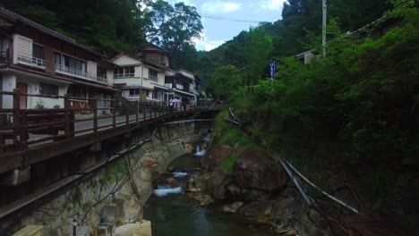 aerial shot moves ahead, capturing the winding watercourse's path through a charming japanese village