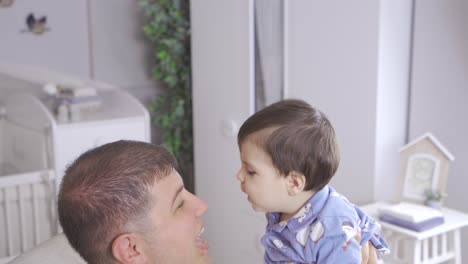 Father-playing-with-his-baby.-He-entertains-and-loves-it.