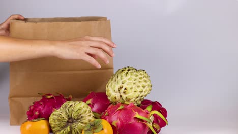 hands placing fruit into a paper bag