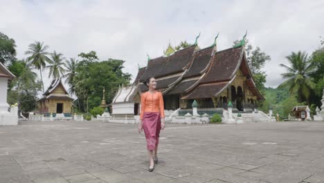 beautiful asian girl walking at wat xieng thong landmark in luang prabang