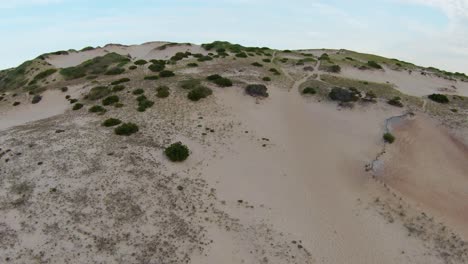 FPV-Drone-shot-of-the-amazing-barren-trails,-sand-dunes,-and-steep-slopes-with-small-bushy-foliage-located-in-Dune-Shacks-Trail-in-Provincetown,-Cape-Cod,-Massachusetts