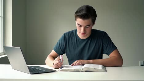 teenager studying with laptop and bible