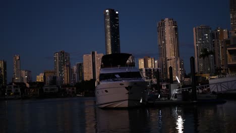 un yate atracado con el horizonte de la ciudad por la noche