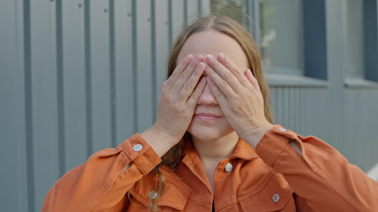 여성은 압도감을 느끼고 손바닥으로 눈을 가리고 얼굴 표정을 숨기고 있습니다.