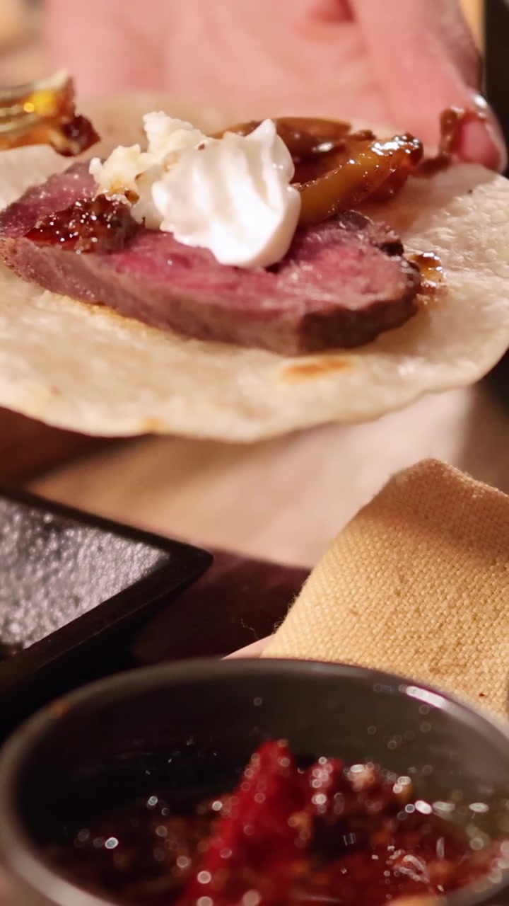 Primo piano della preparazione di fajitas di manzo con tortillas, carne alla griglia e condimenti in un ristorante di Bangkok.