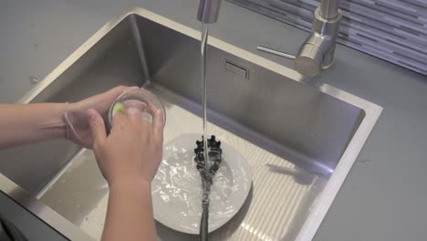 Washing-dishes-with-a-sponge-in-a-kitchen-sink