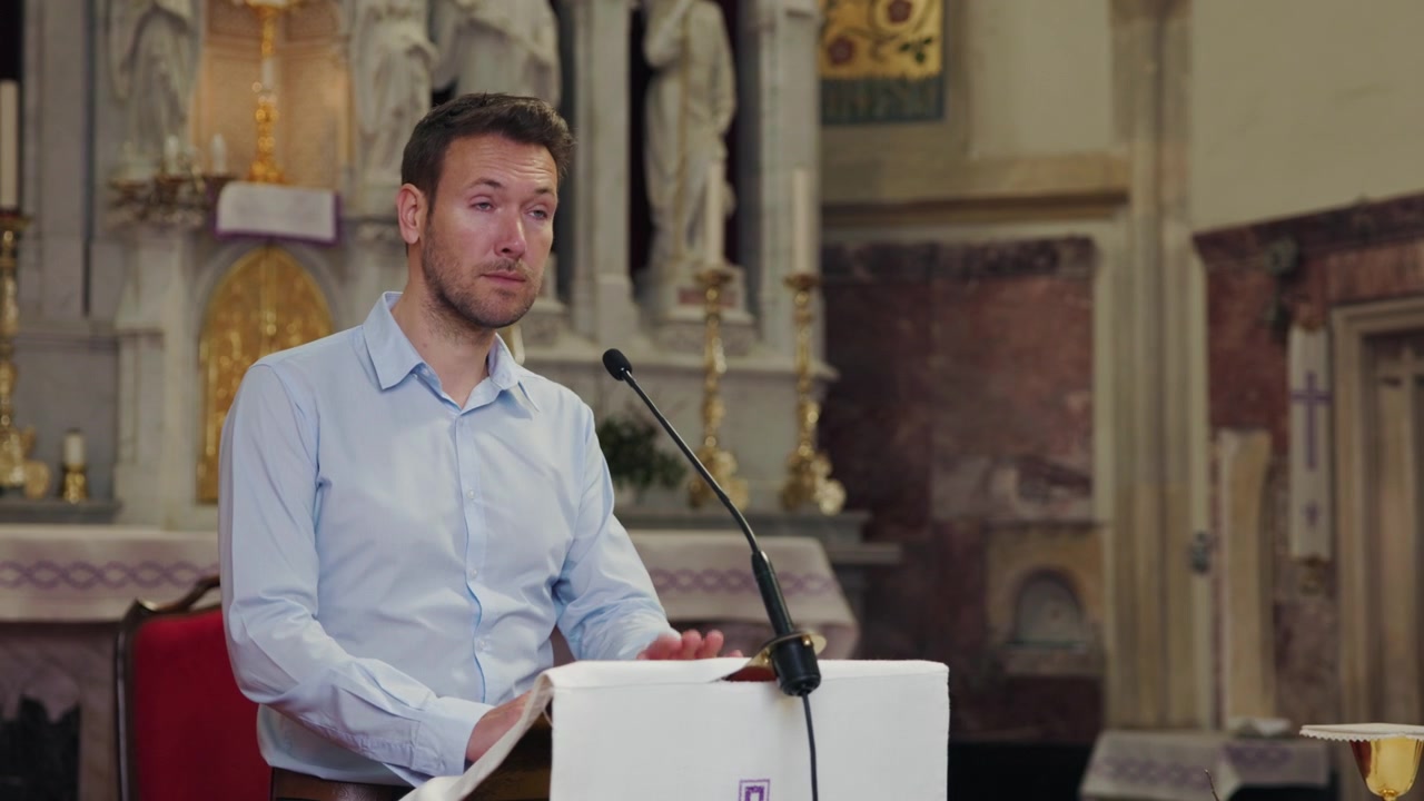Predicatore in piedi dietro un pulpito con un microfono in una chiesa che legge da una Bibbia per pronunciare un