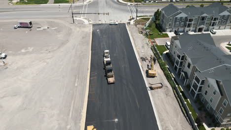 suburban utah roadwork development aerial view flying down new asphalt road and real estate construction