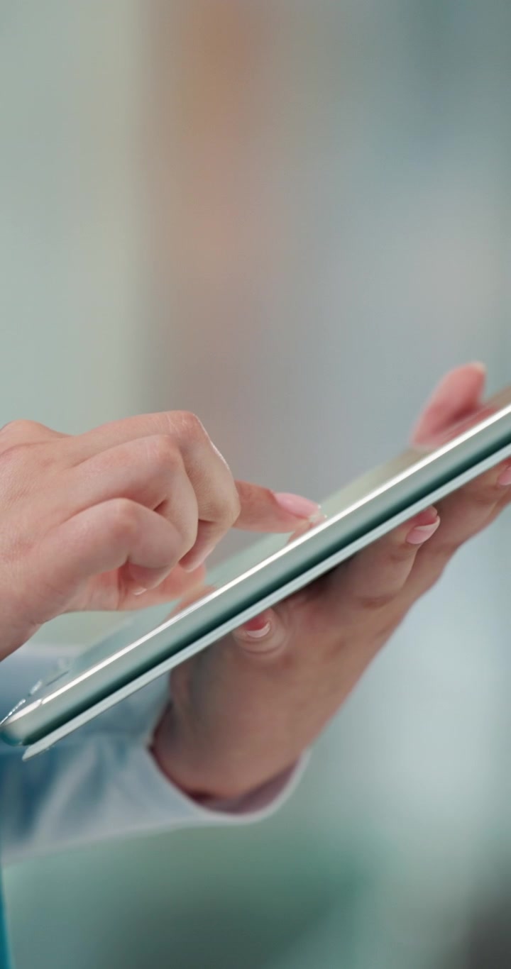 Close-up of a Professional Using a Tablet in a Bright Office