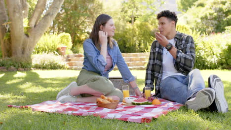 una pareja feliz y diversa tiene un picnic en un jardín soleado, copia el espacio, en cámara lenta.