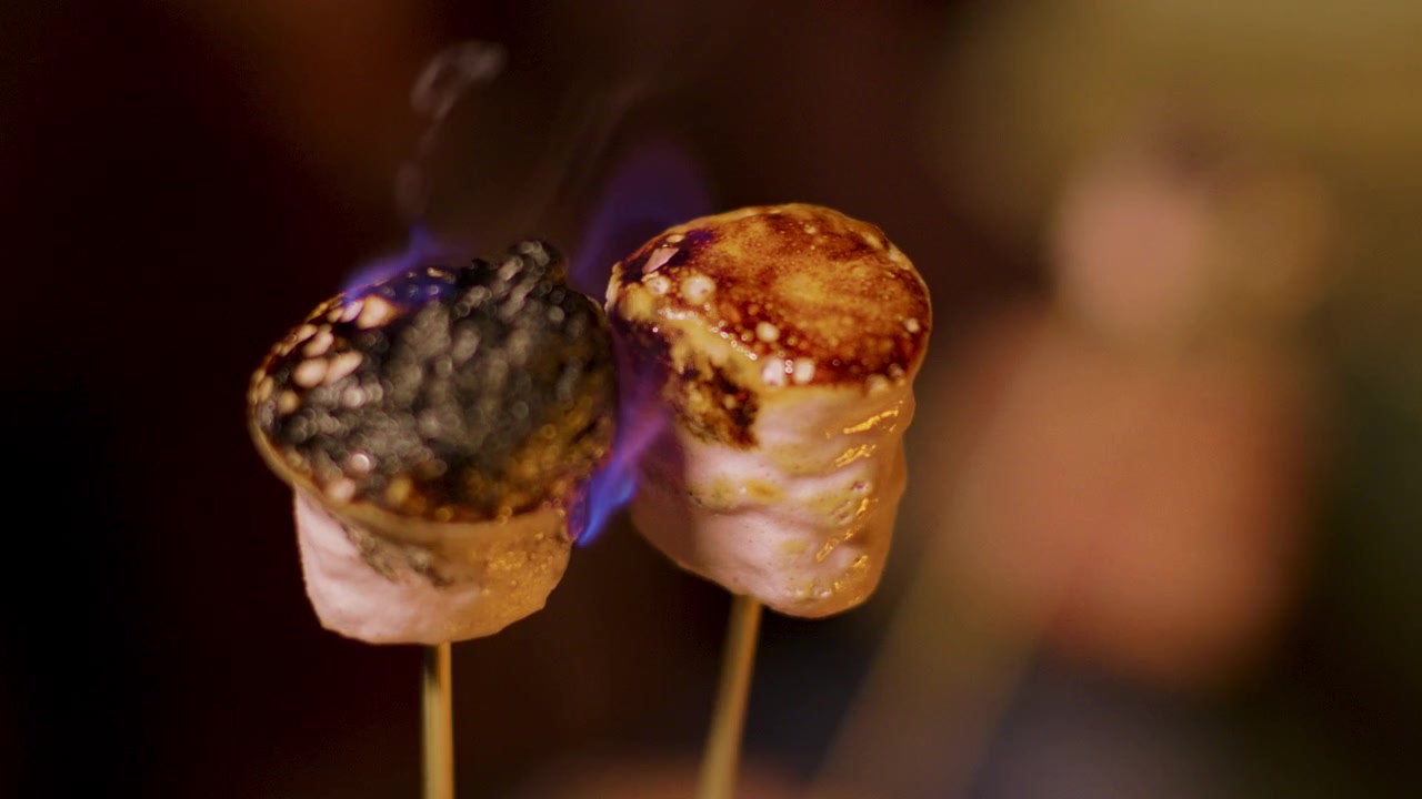 Marshmallow che arrostiscono su bastoncini sopra il fuoco del campeggio.