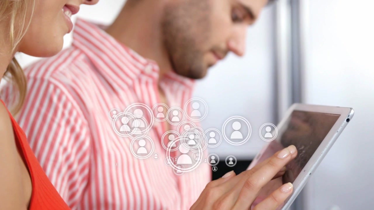 Mujer tocando la tableta y creando iconos sociales flotantes mientras un hombre observa gestionando contactos