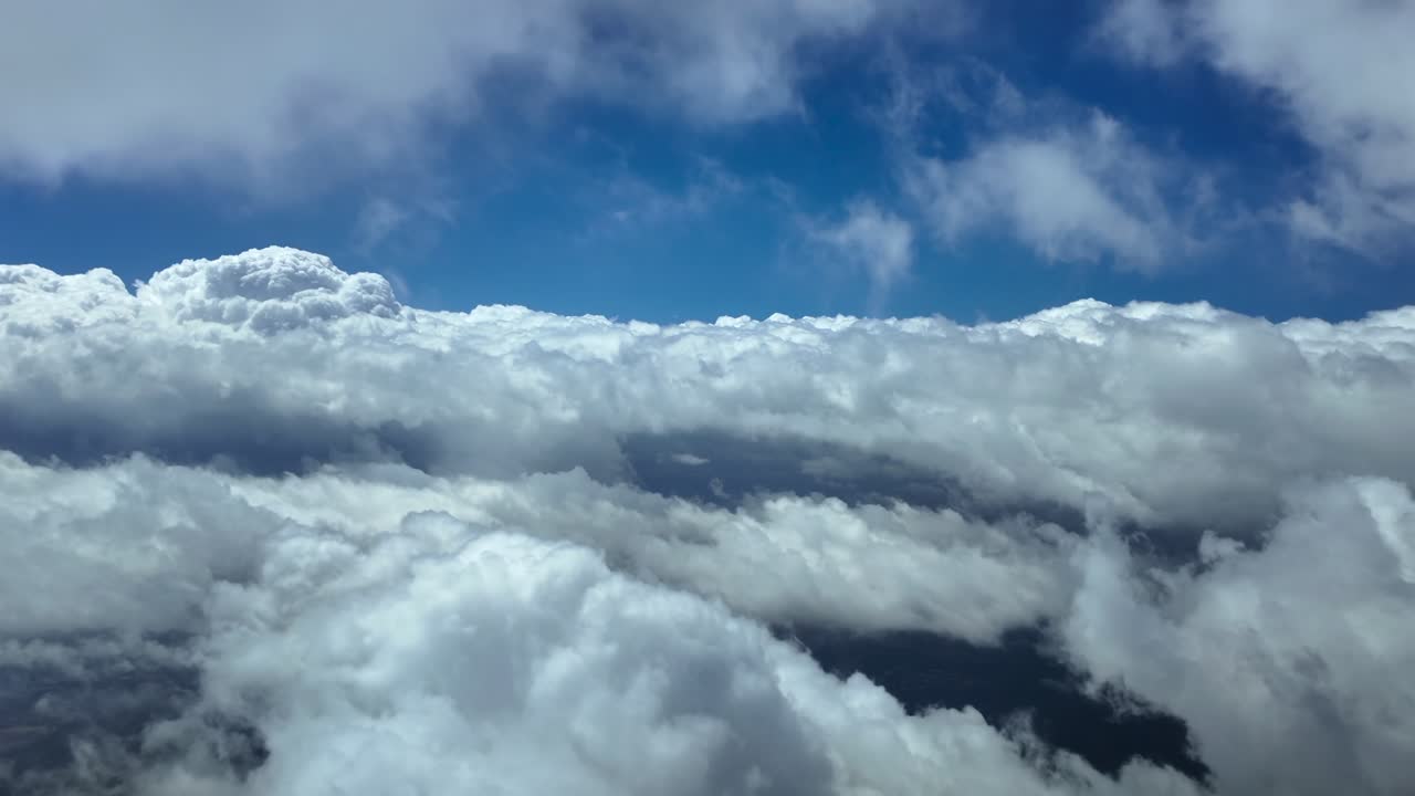 Exclusive POV shot taken from a jet airplane cockpit flying through ethereal fluffy stratus clouds under a deep blue sky. Ultra-realistc 4K shot