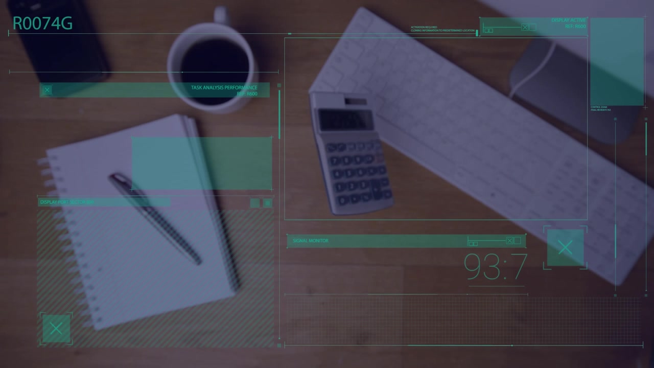A calculator falls onto an office desk next to a computer and a notepad