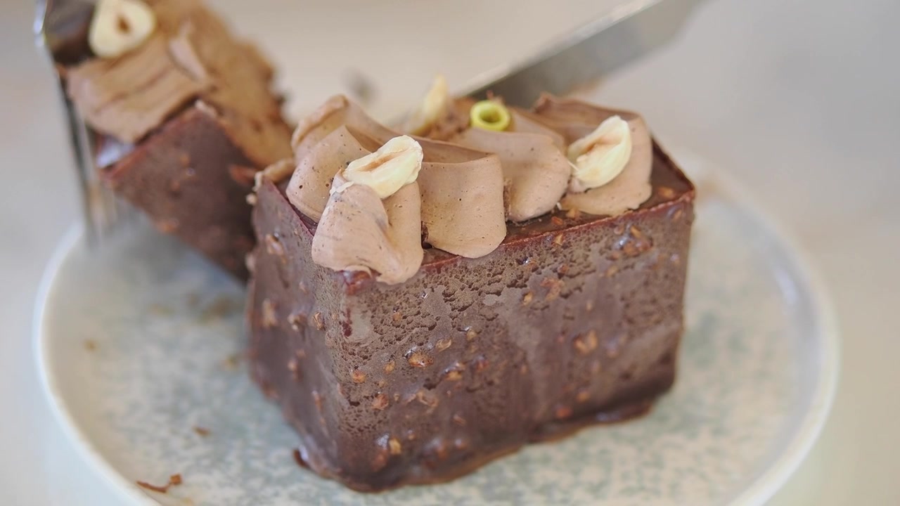 Persona che taglia una fetta di torta al cioccolato e nocciole con un coltello
