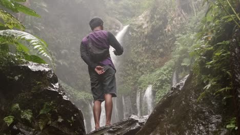 low level shot of a man sanding by a waterfall