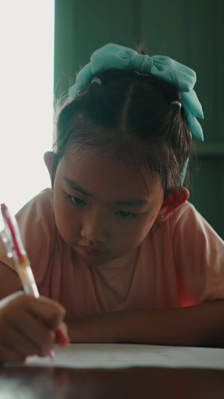 Primo piano di una giovane ragazza asiatica che scrive su carta con una penna