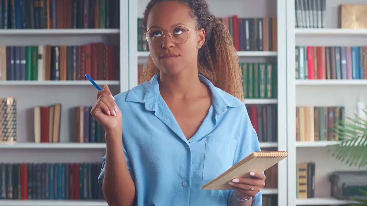 joven afroamericana haciendo notas en el cuaderno de notas se encuentra en la oficina de casa