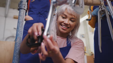 female apprentices in workshop fitting pedals to hand built bicycle frame
