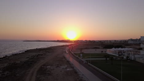 Toma-Aérea-De-Una-Puesta-De-Sol-Sin-Nubes-De-La-Costa-Del-Mar-En-Un-Centro-Vacacional