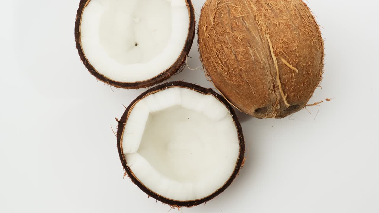 whole and half ripe coconut on a white background, the fruit rotates