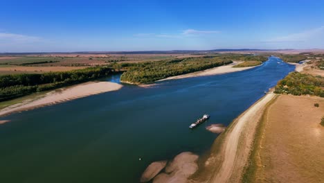 Luftaufnahme-Eines-Baggers,-Der-Ausgebaggerten-Sand-An-Einem-Großen-Fluss-Entlädt,-Sonniger-Tag