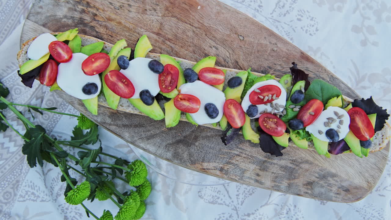 Delicious, healthy, avocado, mozzarella and tomato baguette recipe on a bread board for a perfect picnic meal when on diet - top view