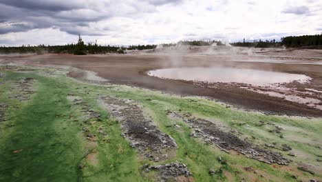 stunning view of geothermal geysers and hot springs with steam clouds rising and ponds at yellowstone national park, wyoming, usa