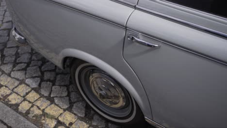 detail of classic car wheel parked on cobblestone street with chrome trim