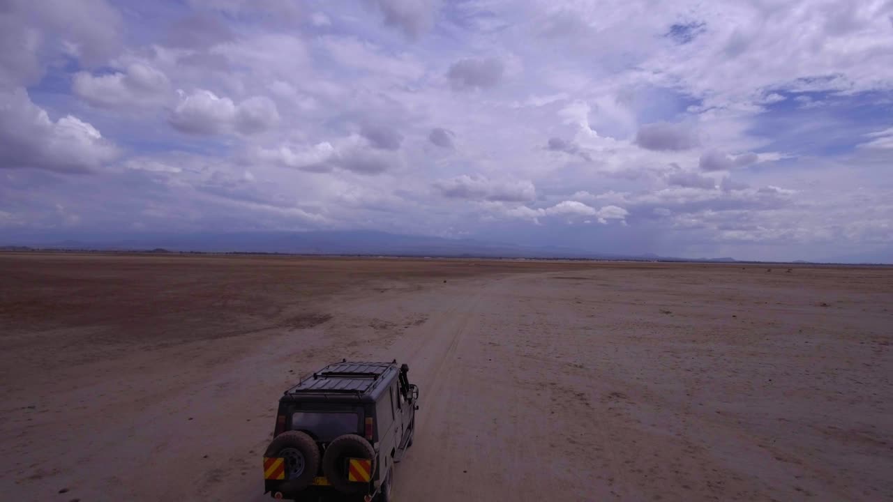 Drone shot of SUV Driving through African savannah. Rangers tracking Poachers. Tourists on safari