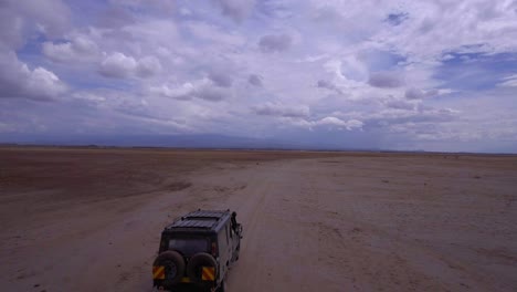 drone shot of suv driving through african savannah. rangers tracking poachers. tourists on safari