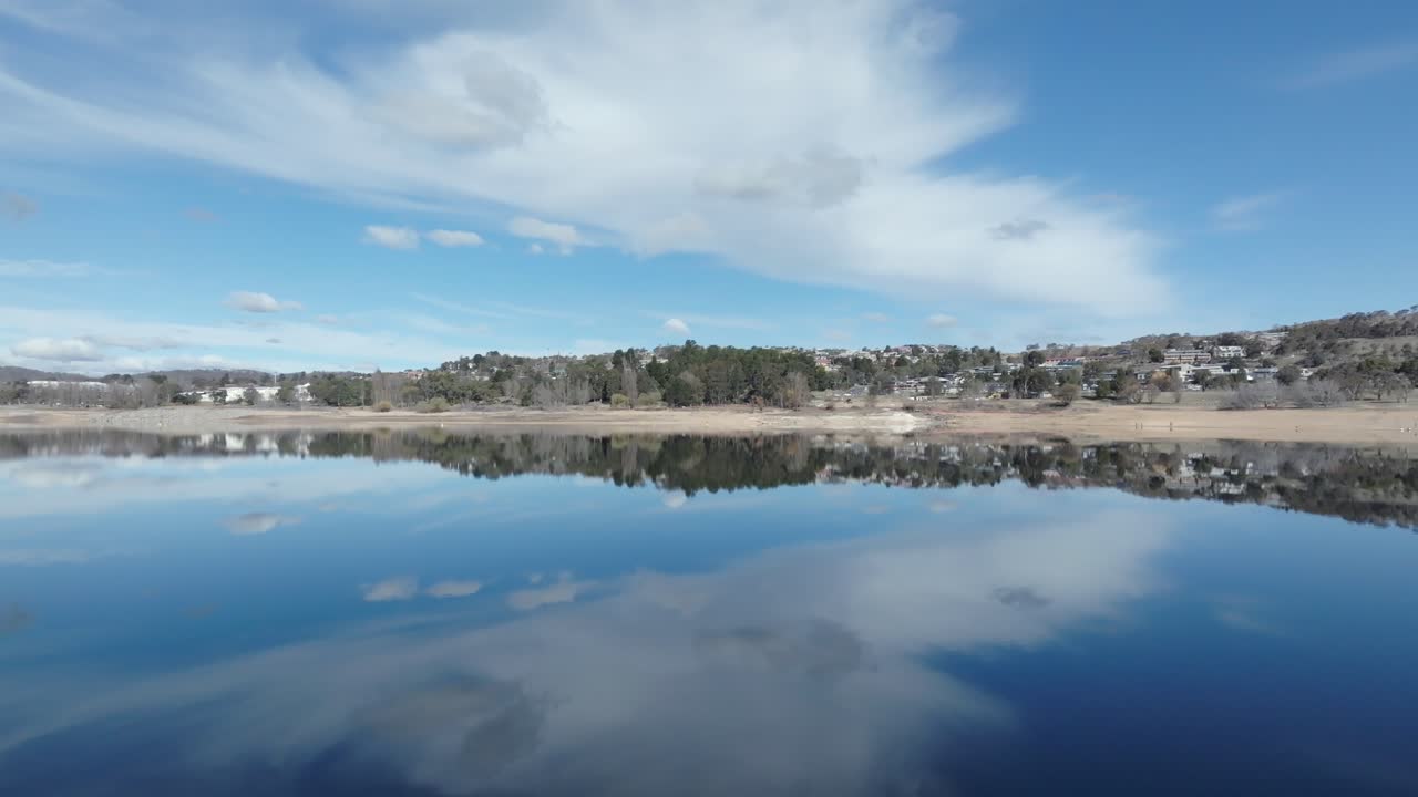 Aerial: Drone rising over lake Jindabyne to reveal the town, NSW, Australia