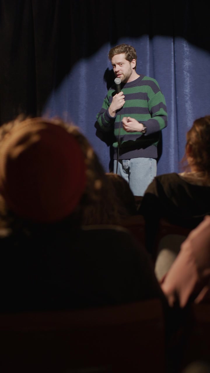 Uomo che si esibisce in uno spettacolo di stand-up comedy a una serata open mic davanti al pubblico