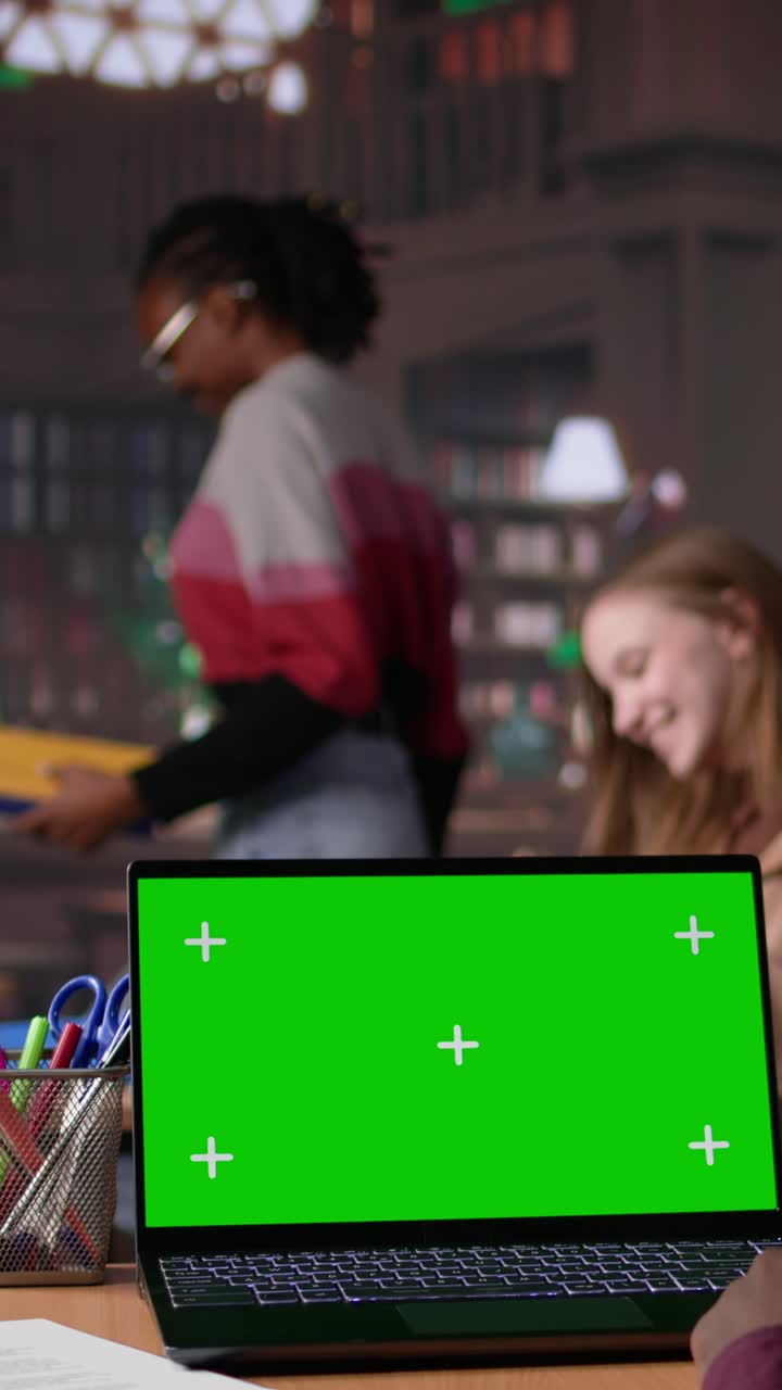 Vertical video young student working with a green screen in the university campus library
