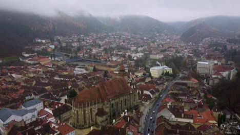 reverse aerial dolly view from drone, overlooking to black church of brasov in a cold winter day - romania