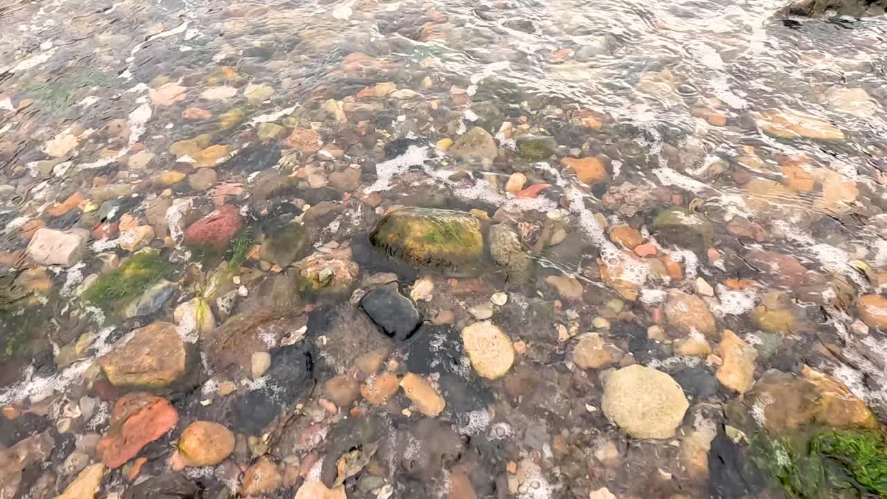 Onde che lambiscono delicatamente rocce colorate sulla spiaggia