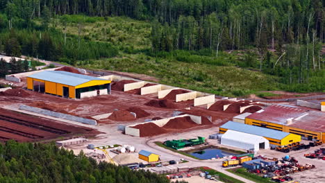 peat processing factory with large piles of raw material and storage sections in forested area