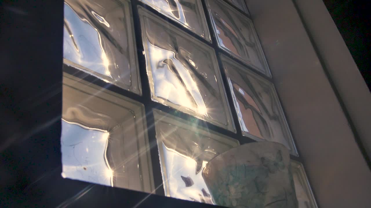 esta es una toma manual que mira las llamaradas del sol mientras brillan a través de una ventana texturizada