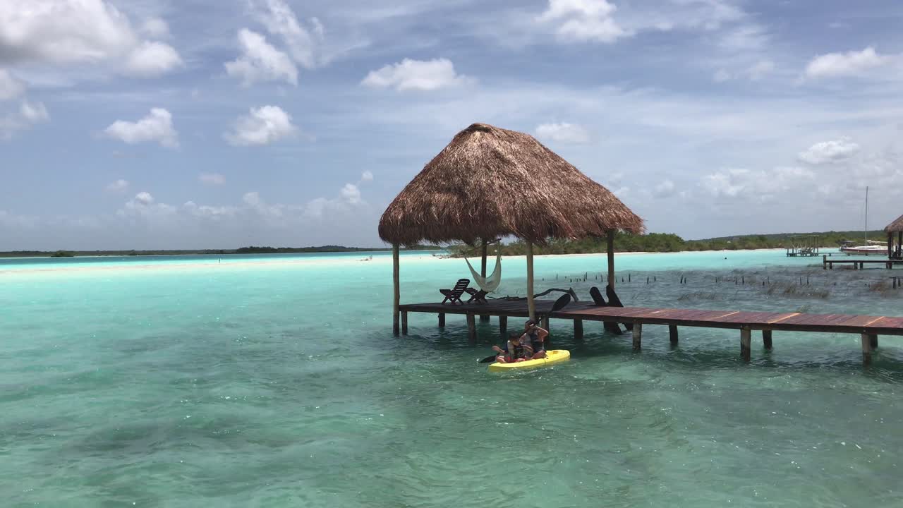 Woman and Kid departing from a Dock in a Kayak in Bacalar Lagoon, Mexico