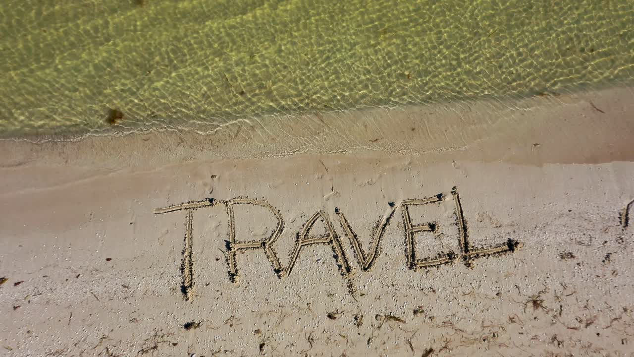 TRAVEL written in the sand gets larger