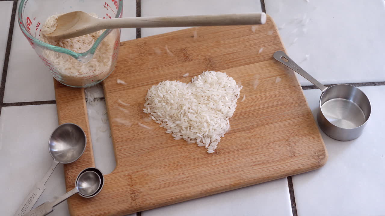 grano de arroz blanco animado formando la forma de un corazón con utensilios de cocina en un bucle de cocina