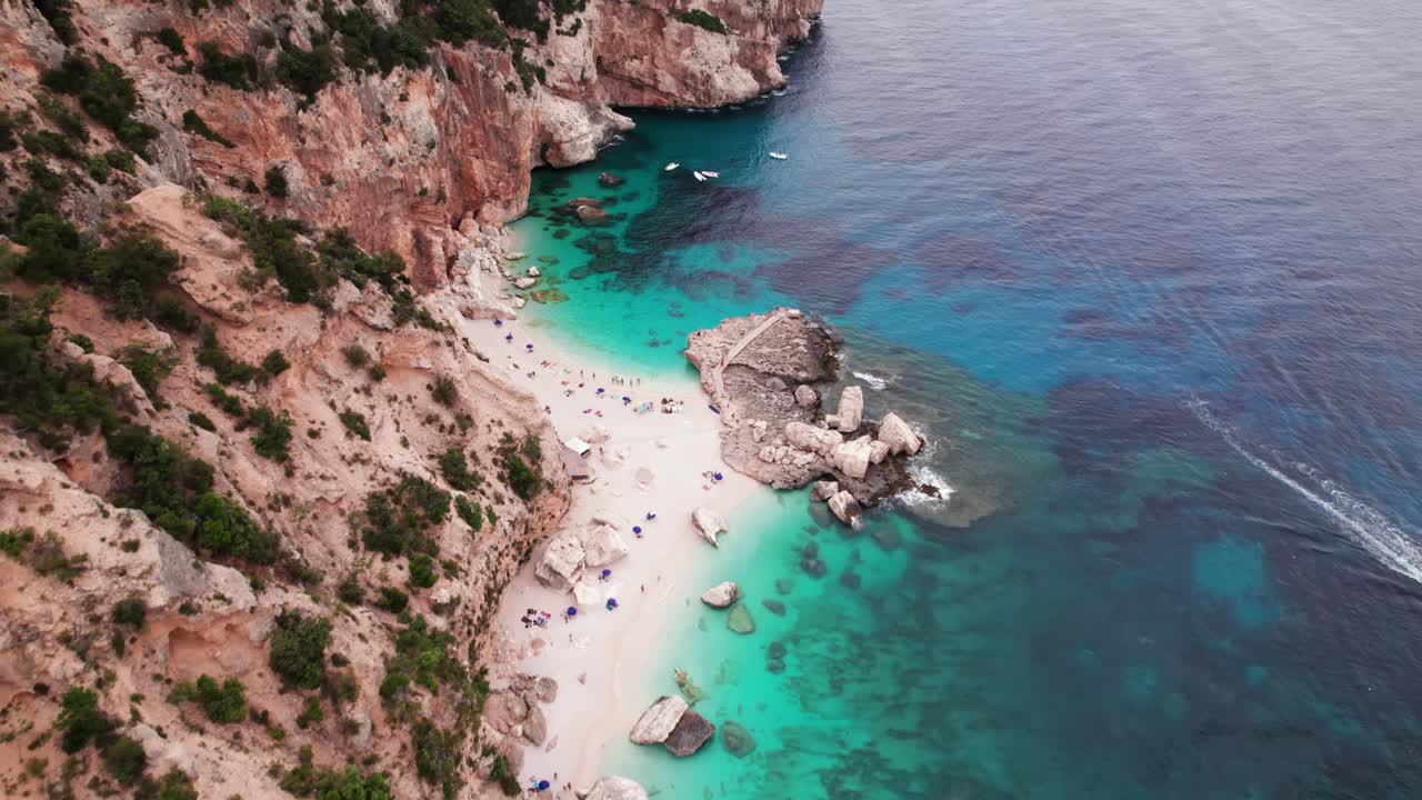 Luftfoto af hvid sandstrand på klippefyldt kystlinje med turkist vand, Sardinien.